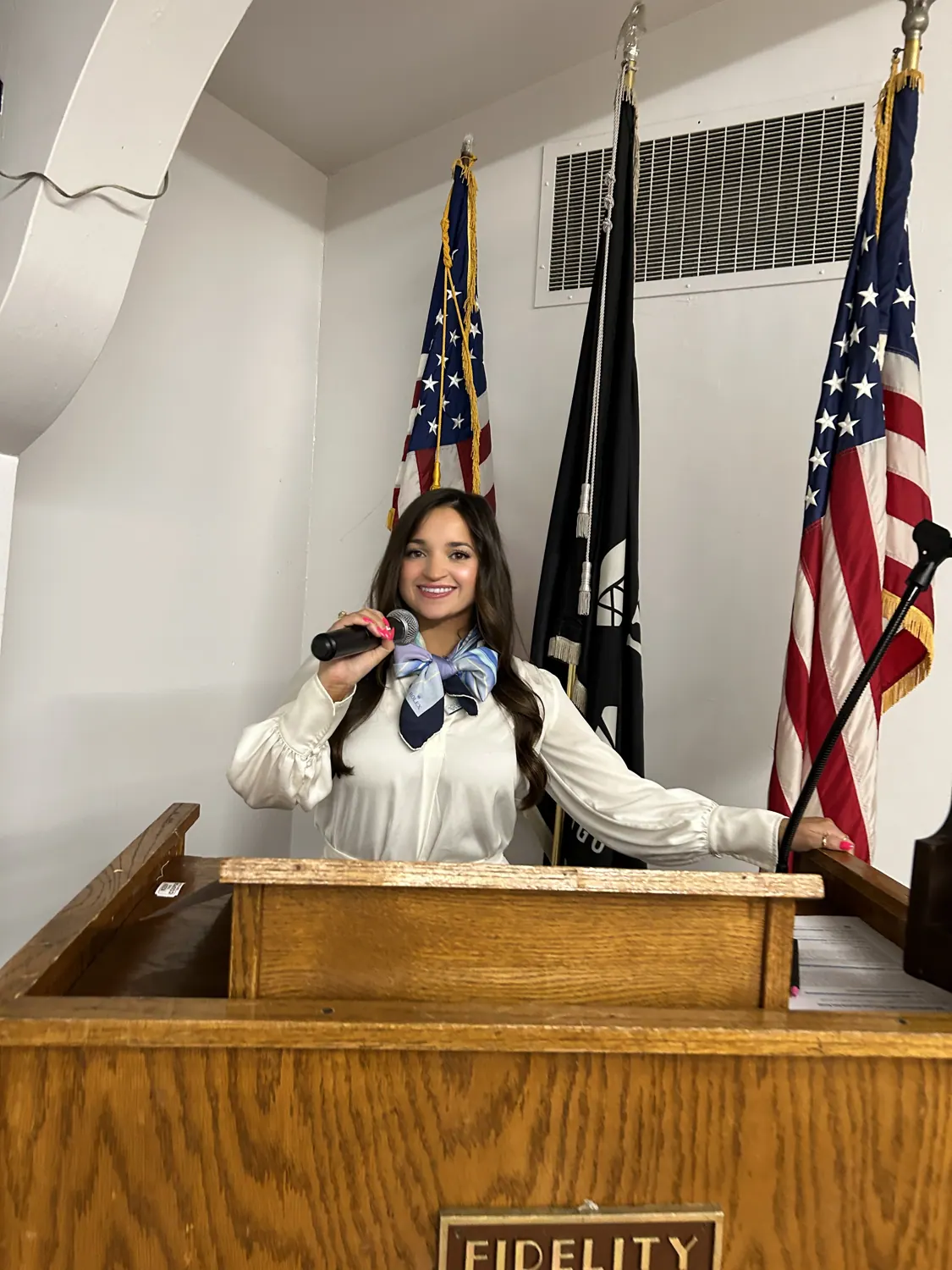 Alissa singing at a ceremony with American flags